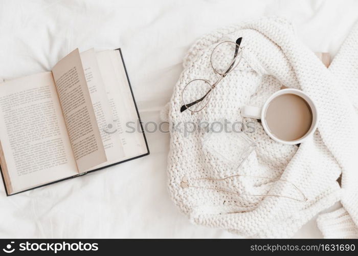 opened novel near sweater with things bedsheet