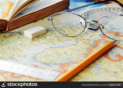 opened old atlas book on map and glasses