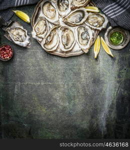 Opened oysters with lemon and various sauces on rustic background, top view, place for text