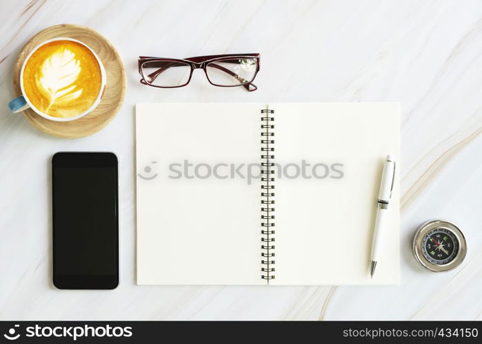 Opened page of notebook with mobile, glasses, compass, pen and coffee cup on white table background. Business workplace concept.