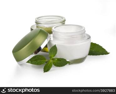 Opened plastic container with cream andgreen leaf on a white background .With clipping path