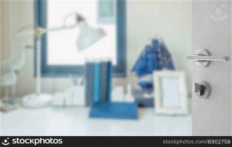 opened white door to blur image of work table with lamp,pencil, book in a home