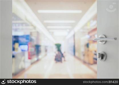 opened white door to blur of department store with bokeh as background.