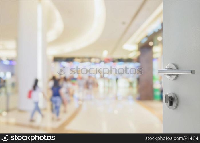 opened white door to blur of people shopping in department store with bokeh as background