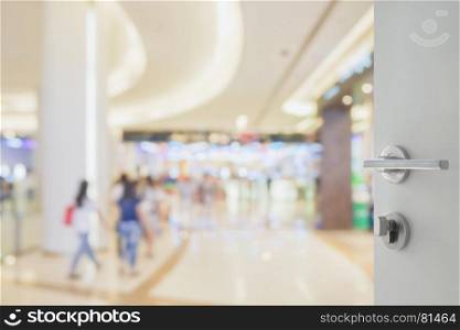 opened white door to blur of people shopping in department store with bokeh as background
