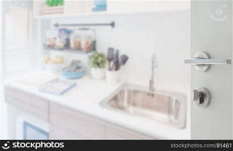 opened white door to kitchen corner with utensil on counter at home