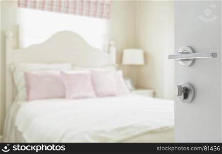 opened white door to luxury bedroom with pillows and desk lamp as blur background