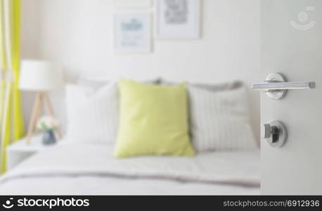 opened white door to modern bedroom with green pillow on bed