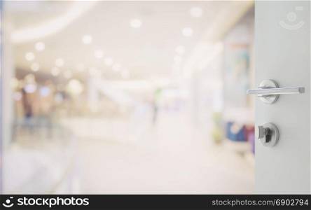 opened white door to shopping mall interior with bokeh as background