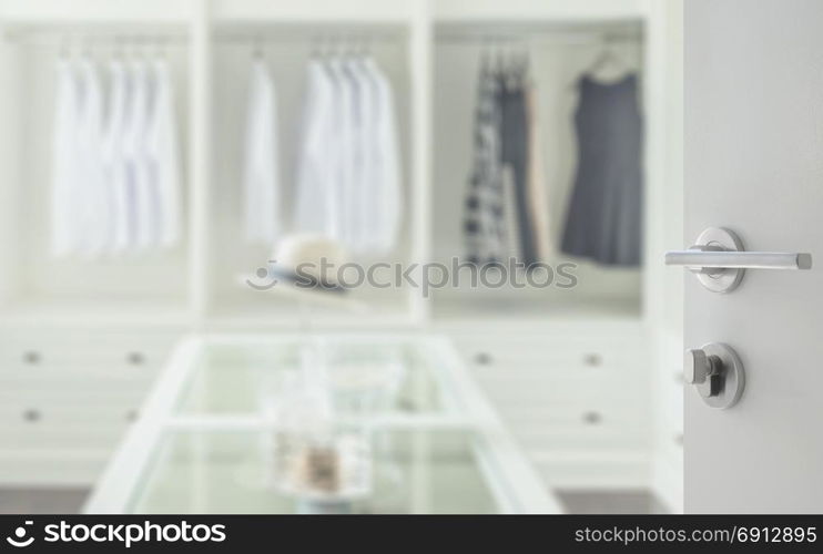 opened white door to walk in closet room with white hat and jewelry set on a dresser table