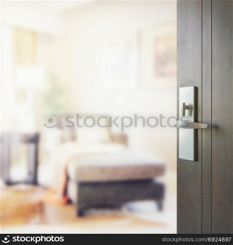 opened wooden door to blurred interior of modern living room