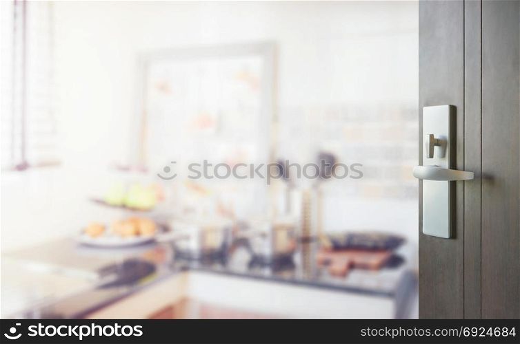 opened wooden door to blurred modern kitchen interior as background