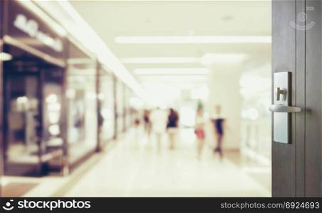 opened wooden door to blurred people shopping in department store with bokeh background.