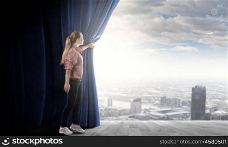 Opening curtain. Young woman in casual opening blue curtain