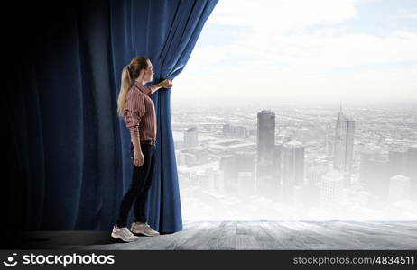 Opening curtain. Young woman in casual opening blue curtain