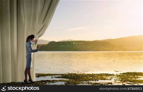 Opening something new. Young businesswoman opening stage curtain to another reality