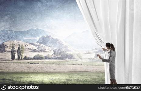 Opening something new. Young businesswoman opening stage curtain to another reality