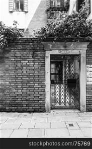 Openwork gate of old house in Venice. Entrance to the home in the medieval italian town. Black and white picture