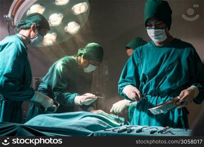 Operating room nurse prepare surgical equipment for surgeon doctor with Medical Team Performing Surgical Operation in Operating Room OR. Medical health care Surgery concept.