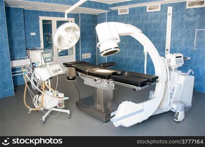 operating room with X-ray medical scan and equipment for artificial lung ventilation of patient.