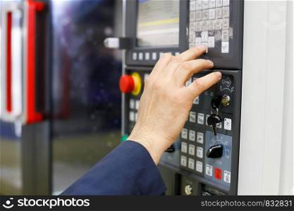 Operator working with CNC machining center using control panel. Selective focus.