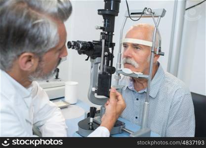 ophthalmologist doing an eye test on an old patient