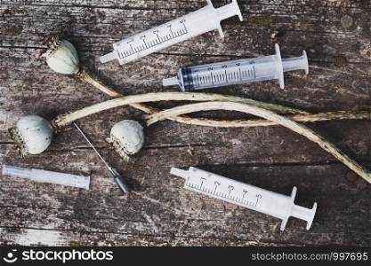 opium poppy seeds and syringes with Needles on wooden background. Addiction