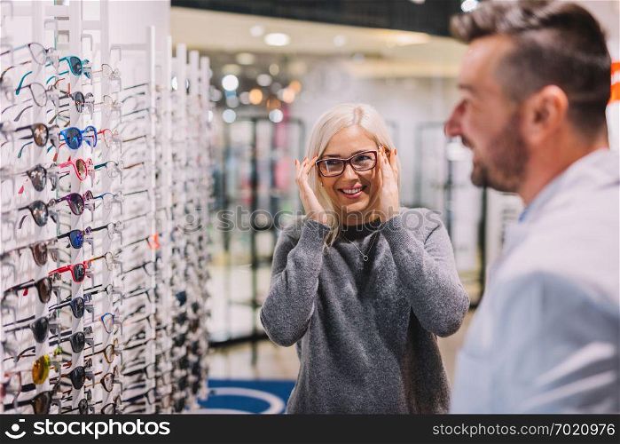 Optician and client choosing glasses together. Optical store, professional consulting.. Optician and client choosing glasses together.