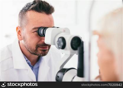 Optician checking his patient&rsquo;s eyes. Medical examination, proffesional optic machine.. Optician checking his patient&rsquo;s eyes.