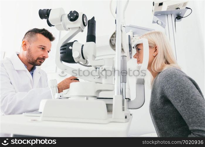 Optician checking woman&rsquo;s eyesight with special equipment. Medicine, healthcare.. Optician checking woman&rsquo;s eyes with special equipment.