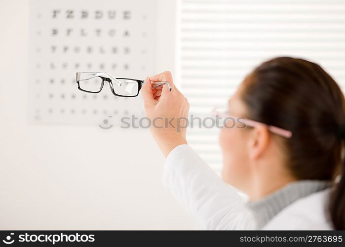 Optician doctor woman with prescription glasses and eye chart