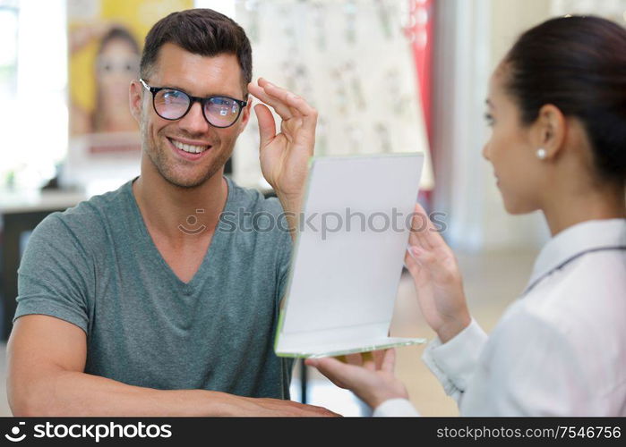 optician holding mirror while client fits the eyeglasses