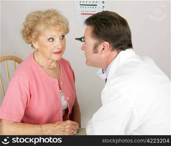 Optician looking into a senior woman&rsquo;s eyes during a routine eye exam.