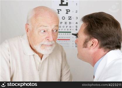 Optician using and ophthalmoscope to look into a patient&rsquo;s eyes.