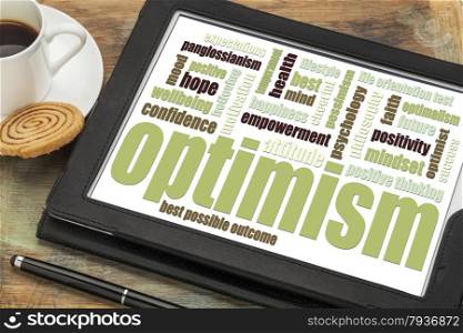 optimism word cloud on a digital tablet with a cup of coffee