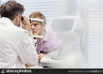 Optometrist examining patient on phoropter at hospital