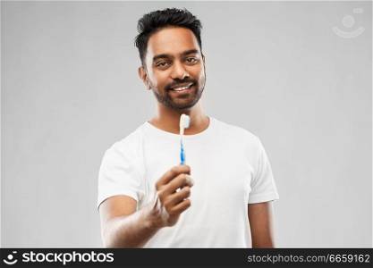 oral care, dental hygiene and people concept - smiling young indian man with toothbrush over gray background. indian man with toothbrush over gray background