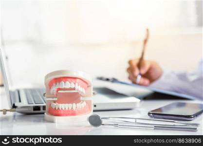Oral dental. Dentist doctor in uniform writing information of patient in paperwork checklist on clipboard on desk office, teeth model, X-ray on laptop screen, prescription medical dental healthcare