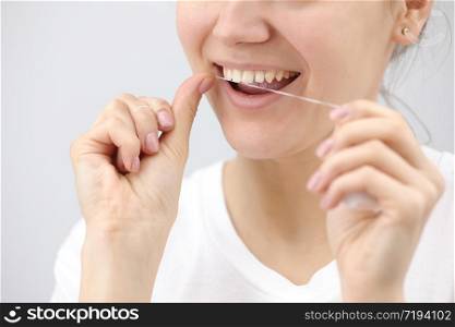 Oral hygiene and health care. Smiling women use dental floss of white healthy teeth on a white background. place for inscription.. Oral hygiene and health care. Smiling women use dental floss of white healthy teeth on a white background. place for inscription