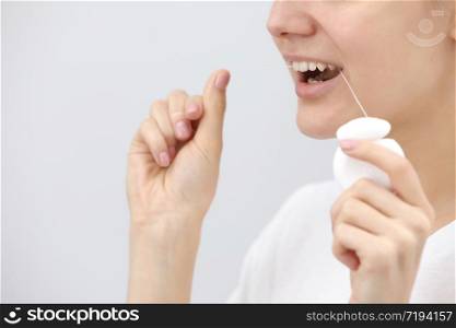 Oral hygiene and health care. Smiling women use dental floss of white healthy teeth on a white background. place for inscription.. Oral hygiene and health care. Smiling women use dental floss of white healthy teeth on a white background. place for inscription