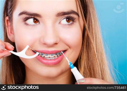 Oral hygiene concept. Woman with braces cleaning teeth with toothbrush and dental floss. Woman with braces cleaning teeth with toothbrush