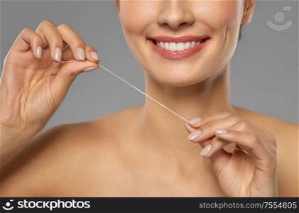 oral hygiene, dental care and health concept - close up of smiling young woman with floss cleaning teeth. smiling woman with dental floss cleaning teeth
