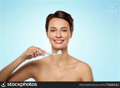 oral hygiene, dental care and health concept - smiling woman with toothpaste on toothbrush cleaning teeth over blue background. smiling woman with toothbrush cleaning teeth
