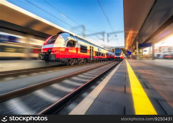 Oran≥high speed train in motion on the railway station at sunset. Fast moving modern∫ercity train and blurred background. Railway platform. Railroad in Austria. Passen≥r transportation. Concept 