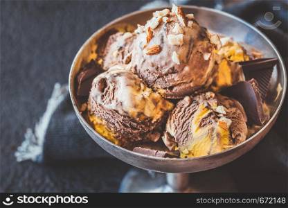 Orange and chocolate ice creamdecorated with crushed nuts in vintage vase