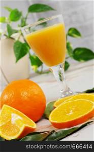 orange and glass of orange juice on a white wooden table