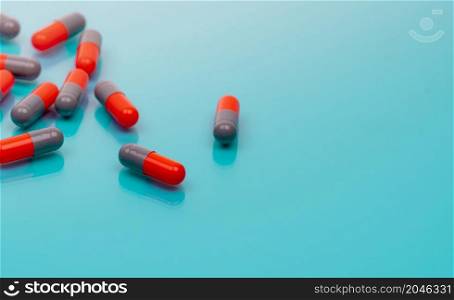 Orange and gray capsule pills on blue background. Pharmaceutical industry. Prescription drugs. Healthcare and medicine. Pharmacy web banner. New drug research and development. Health science.
