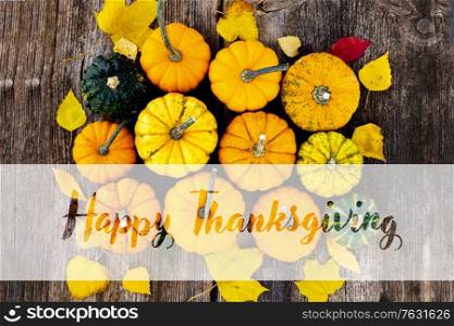 orange and green raw pumpkins on old wooden textured table, top view with happy thanksgiving greetings. pumpkin on table