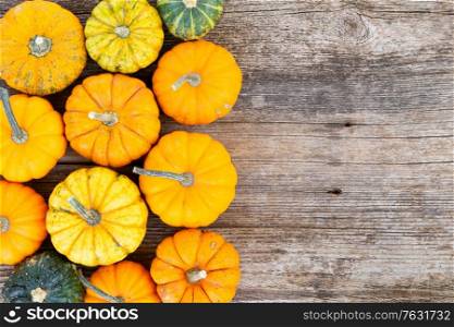 orange and green raw pumpkins on old wooden textured table, top view border with copy space. pumpkin on table
