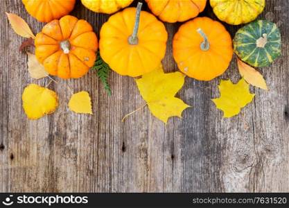 orange and green raw pumpkins on old wooden textured table, top view flat lay border. pumpkin on table